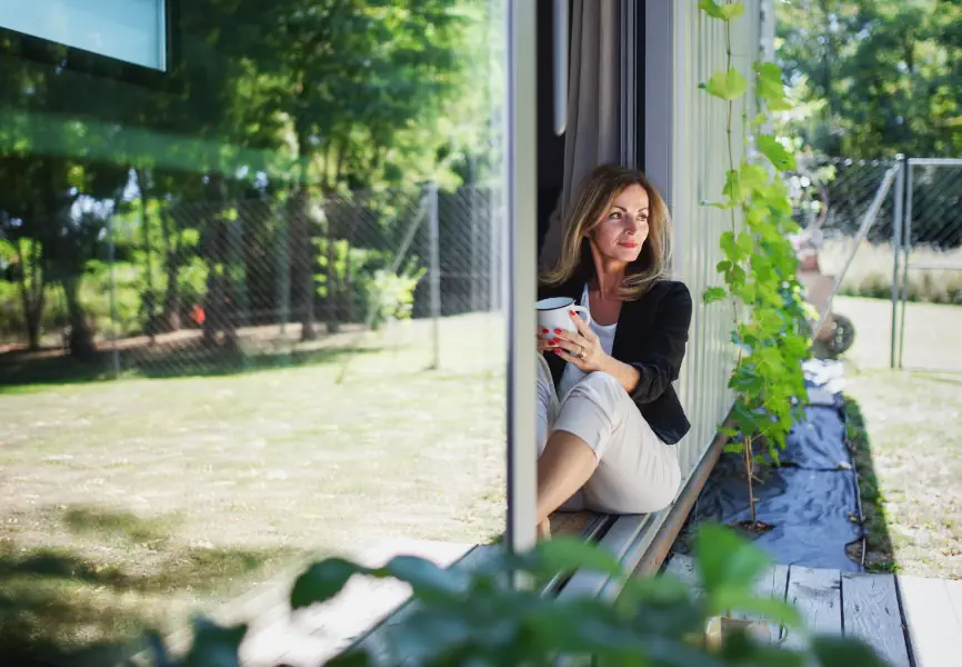 En kvinna kopplar av på verandan vid sitt containerhus